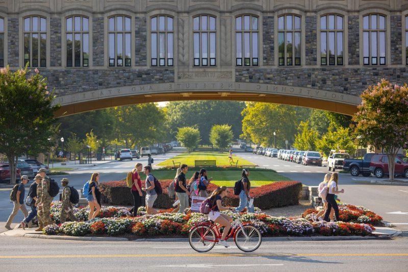 学生 walk and bike in front of Torgersen Bridge.